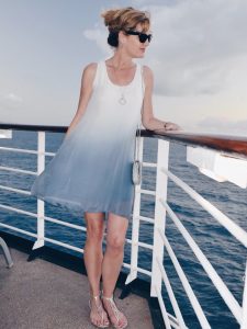 Woman standing on cruise ship in blue and white sun dress