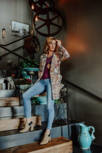 woman standing on stairs modeling floral coat with jeans