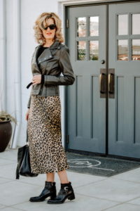 woman wearing leopard skirt with faux leather jacket and boots