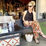 woman wearing orange floral pants and black shirt on restaurant patio