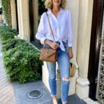 classic women's spring outfit with distressed jeans, white linen blouse, and leopard shoes